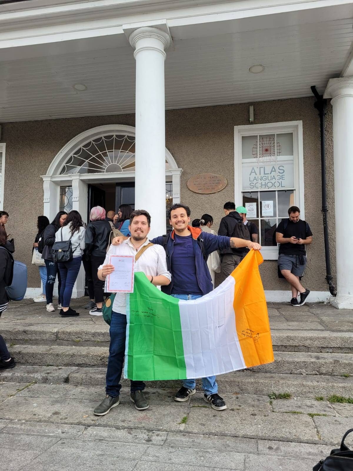 Marcelo con su amigo Luis y la bandera irlandesa afuera de Atlas Language School, el día de una graduación